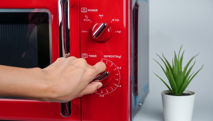 Closeup of someone setting the defrost on the microwave