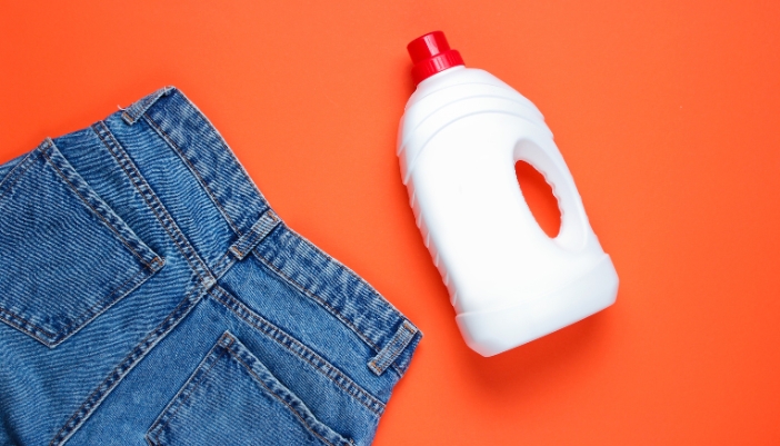 Closeup of a bottle of liquid detergent next to a pair of pants