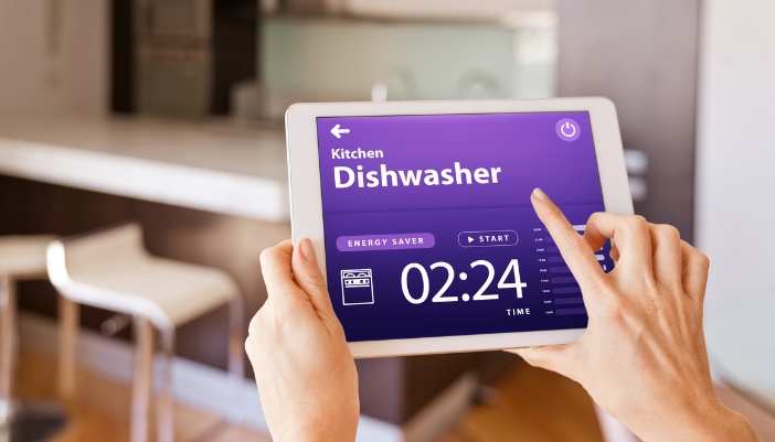 A closeup of someone checking on dishwasher cycle with smart home tablet