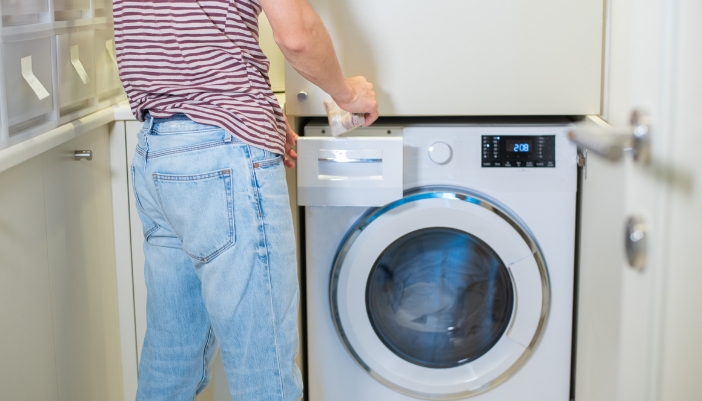 Closeup of someone filling a high-efficiency washer with detergent