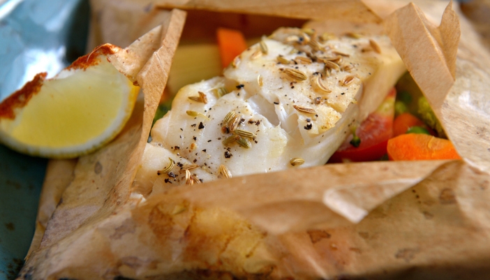 A parchment paper pouch filled with fish and veggies