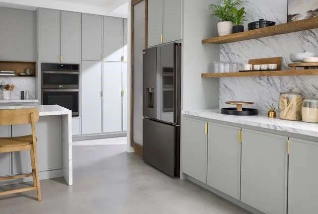 side view of a modern kitchen with grey cabinetry and a dark grey stainless steel counter depth refrigerator