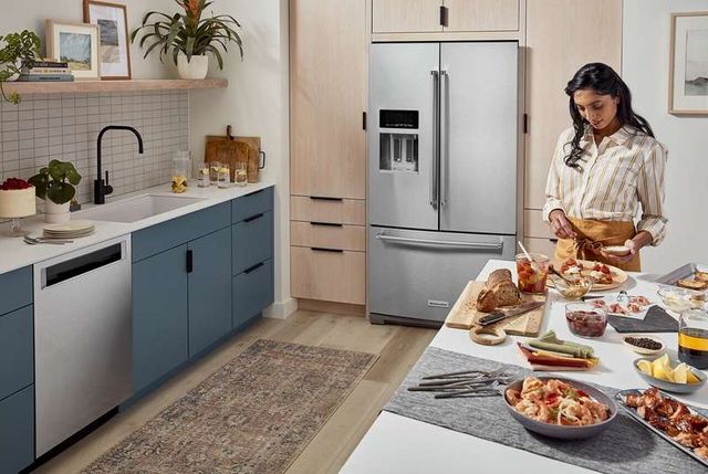front view of a woman standing making appetizers in a modern kitchen with a french door refrigerator 