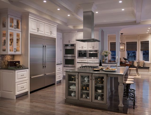 front view of a dimly lit luxury kitchen with stainless steel appliances throughout