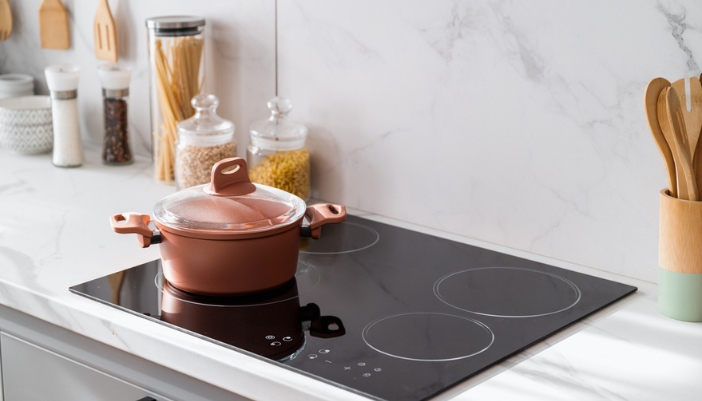 A copper pot sits alone on an induction cooktop.