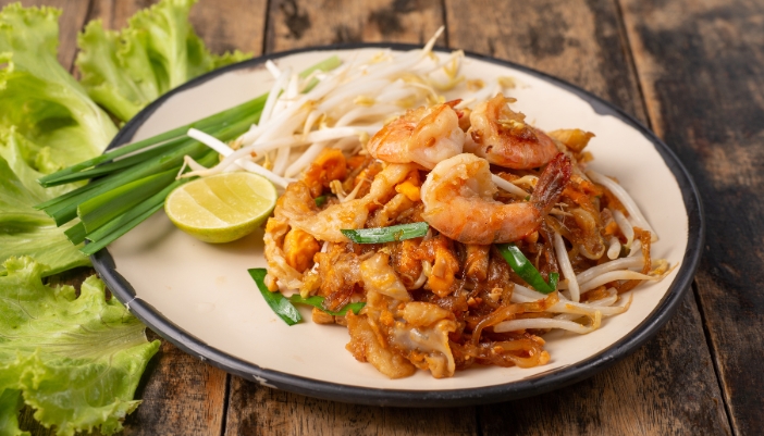 A plate of shrimp pad Thai and a small side salad.