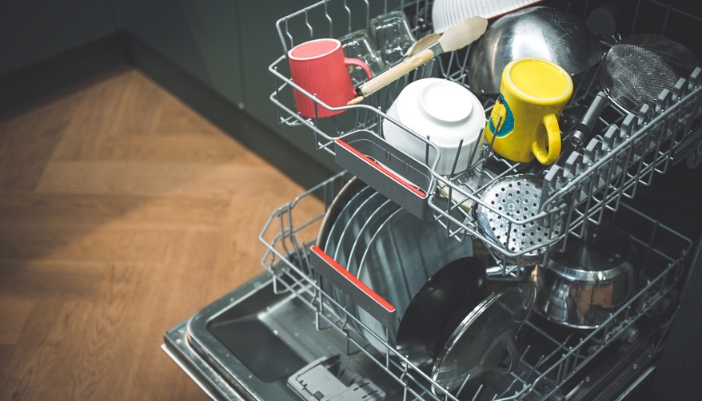 An open dishwasher in a kitchen that’s filled with a variety of dishes.