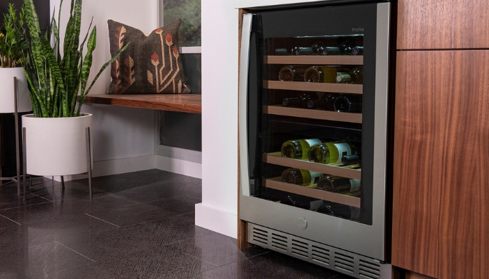 A close-up of a stainless steel wine fridge in a wooden cupboard.