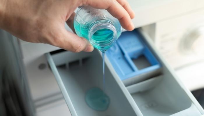 Hand dripping some detergent into dispenser