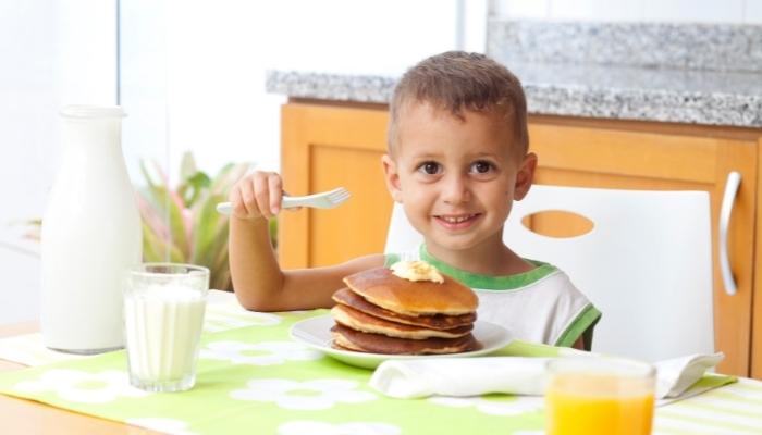 Little boy eating banana pancakes