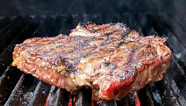 Front view of a large steak being smoked on a smoker