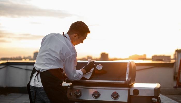 man wiping down his gas grill