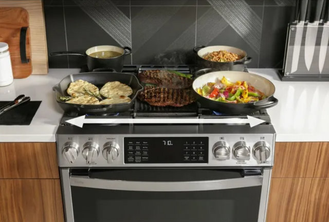 front view of a 30 inch gas range with various foods cooking on top, and a white arrow stretching the width of the range 