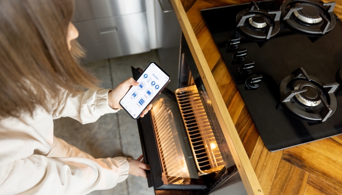 Woman using her smartphone to operate her smart oven