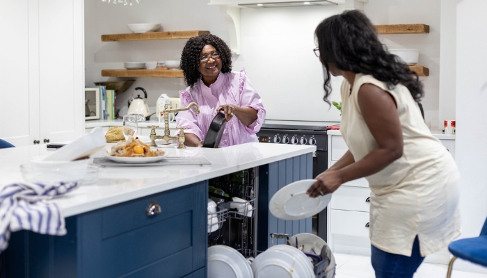 Mother and daughter cleaning up after dinner and loading the dishwasher