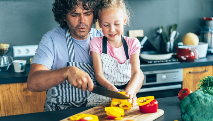 Dad helping his daughter chop bell peppers
