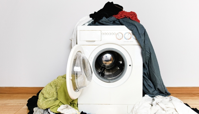 Washer-dryer combo surrounded by piles of laundry