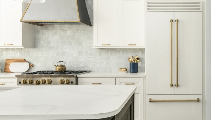 A white, modern kitchen with white appliances and a wooden island