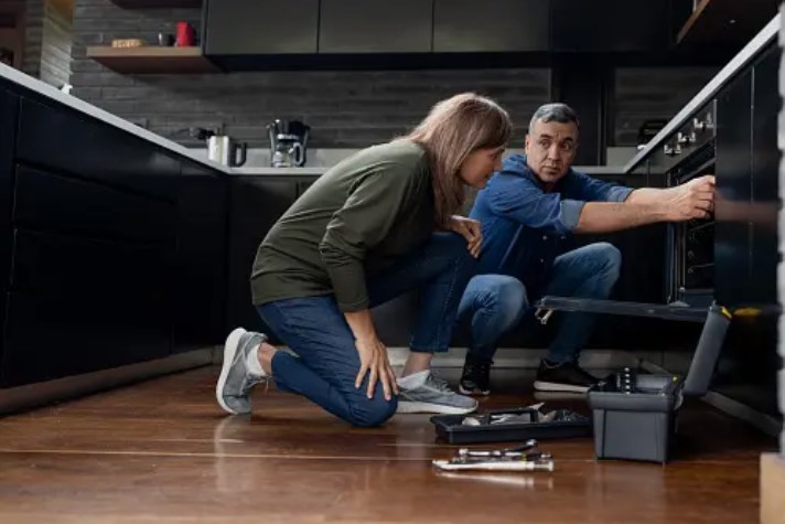 two people fixing an appliance in a modern kitchen
