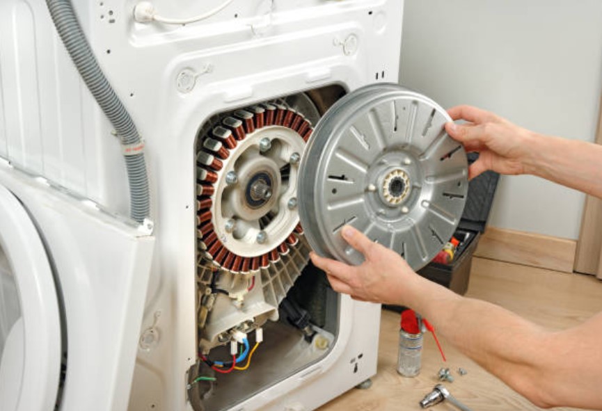a dryer being repaired and arms holding a repair part