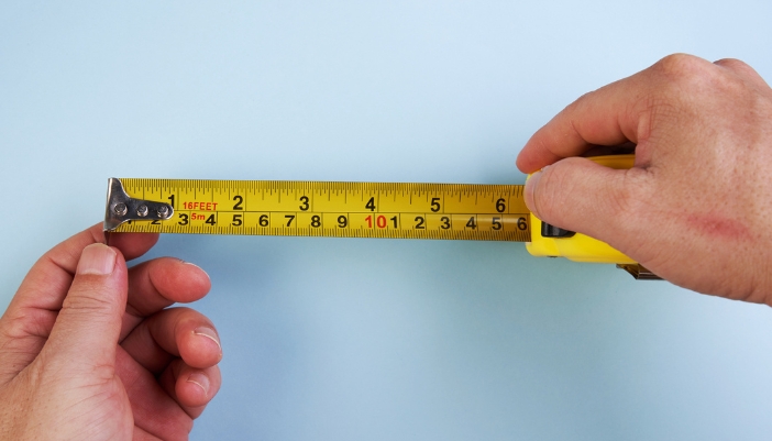 A concept image of someone holding an extended measuring tape over a blue background