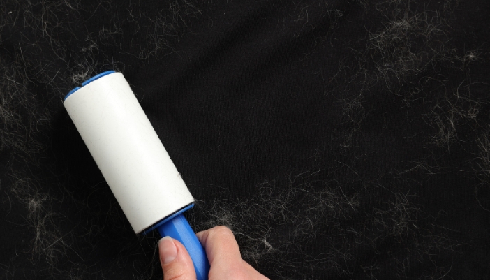Closeup of someone using a lint roller on their clothes to remove pet hair