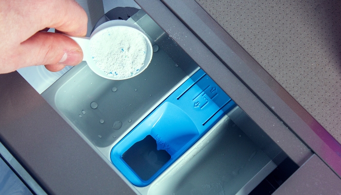 Closeup of someone adding detergent to washer