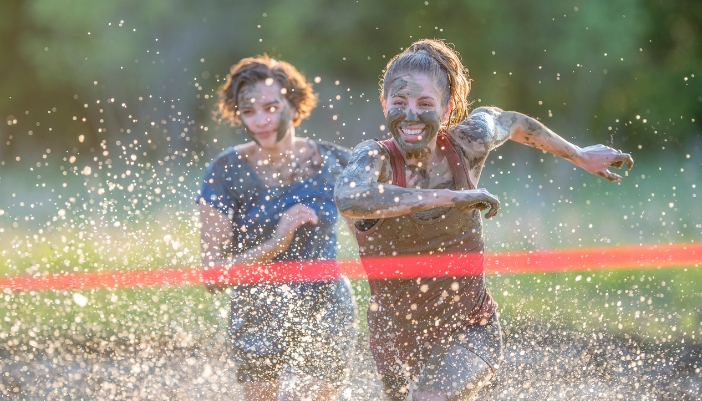 Two people racing to the finish line of summer mud run