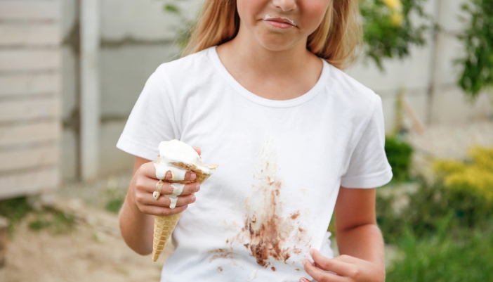 Closeup of a child holding up an ice cream cone and a stained shirt