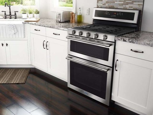 front view of a modern kitchen with a stainless steel double oven gas range built into a white countertop