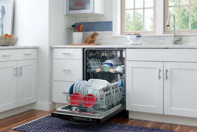 front view of a modern kitchen with white cabinetry and an open, full, stainless steel dishwasher