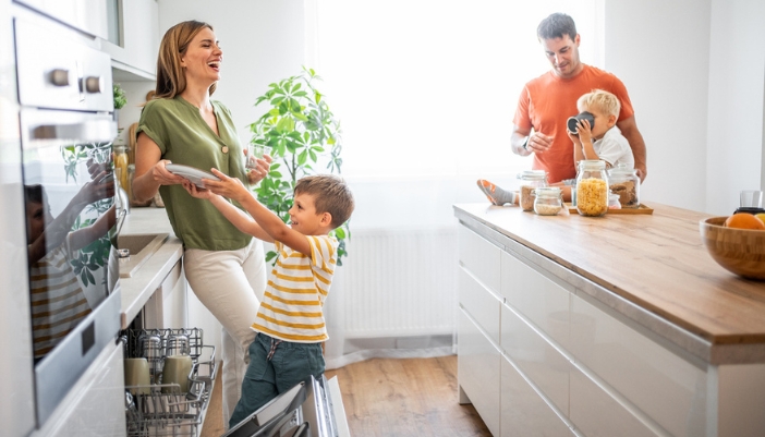 A family spends time in the kitchen together to unload a dishwasher and complete chores.