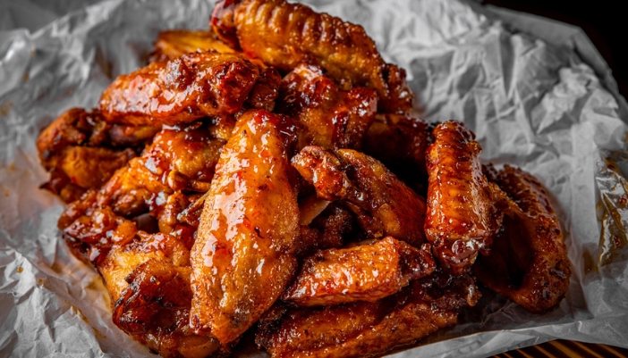Sweet and spicy chicken wings on an aluminum foil plate.