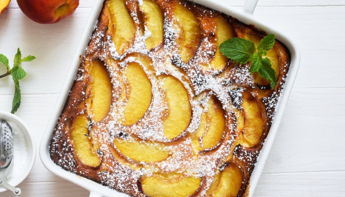 A peach pound cake in a baking dish on a neutral background.