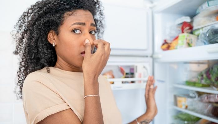 woman smelling stinky fridge