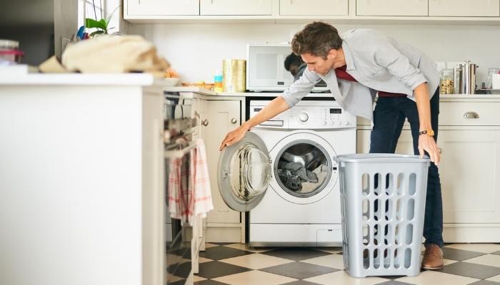 young man using a washer dryer combo to do his laundry