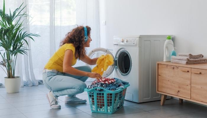 young woman doing laundry while listening to music