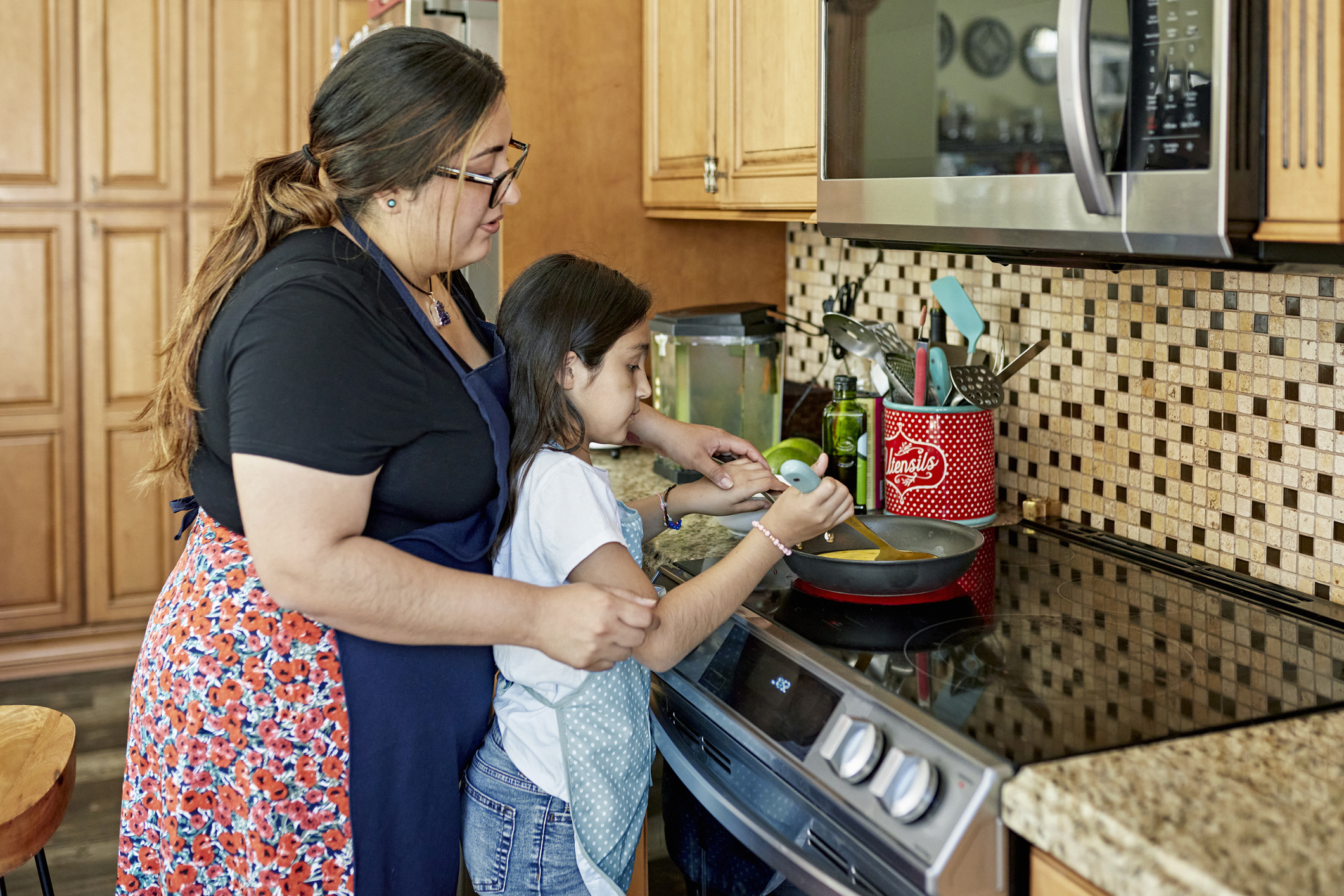 mother and daughter cooking together on induction range 