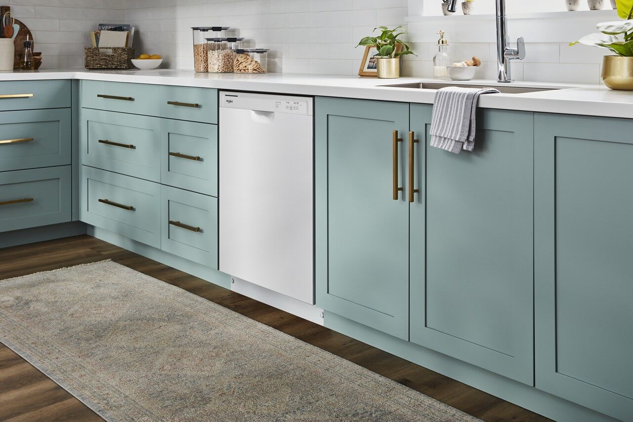 white dishwasher surrounded by teal cabinetry 