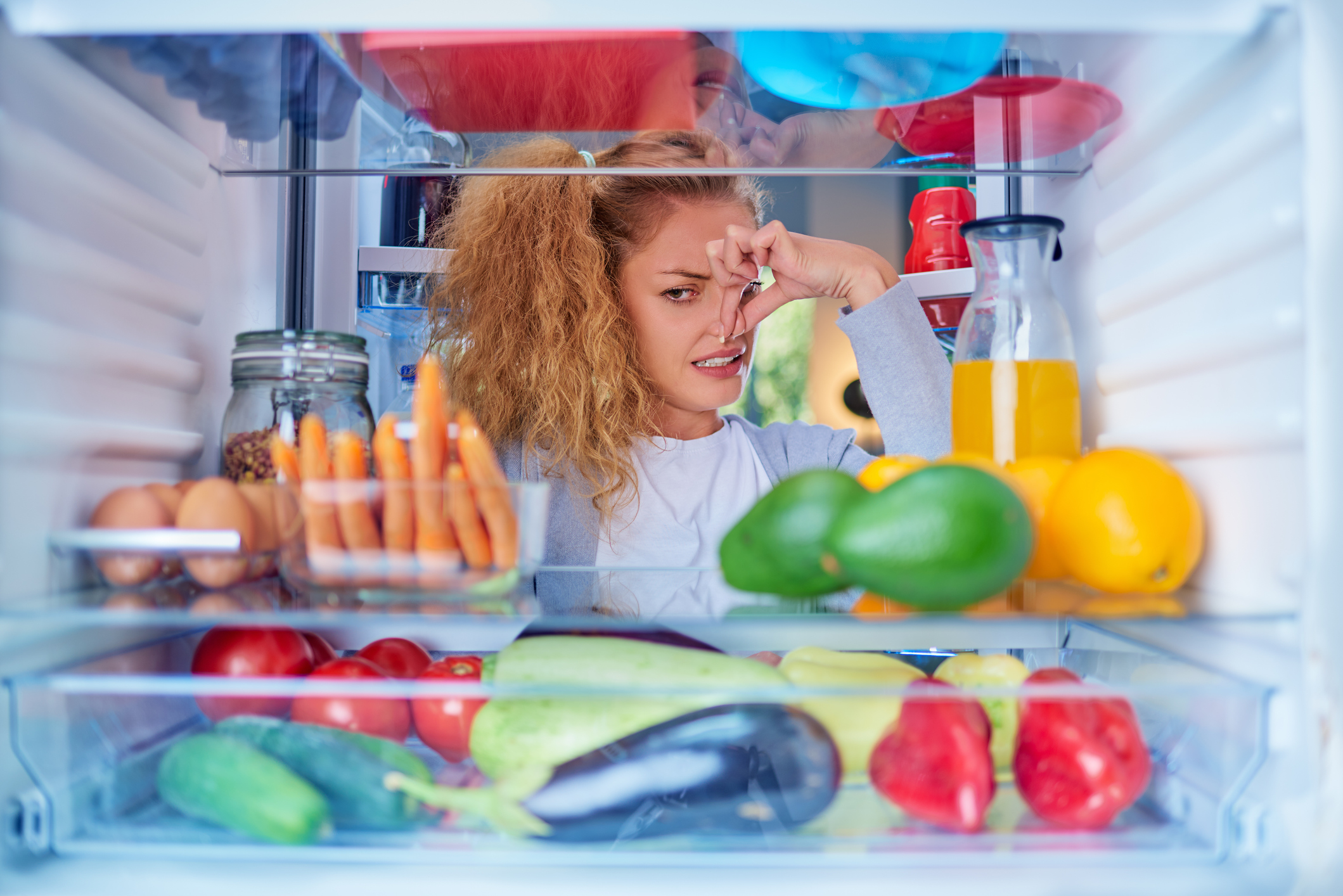 woman holding nose because of smelly fridge
