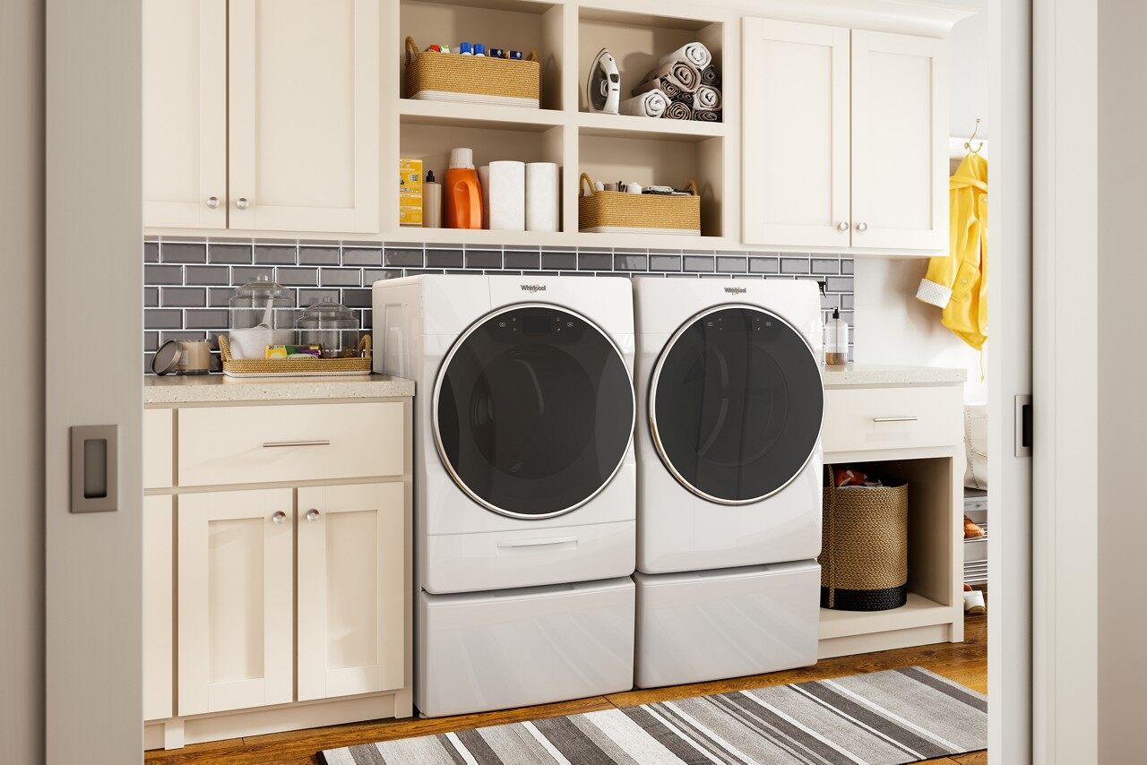 man taking clothes out of whirlpool dryer of laundry pair