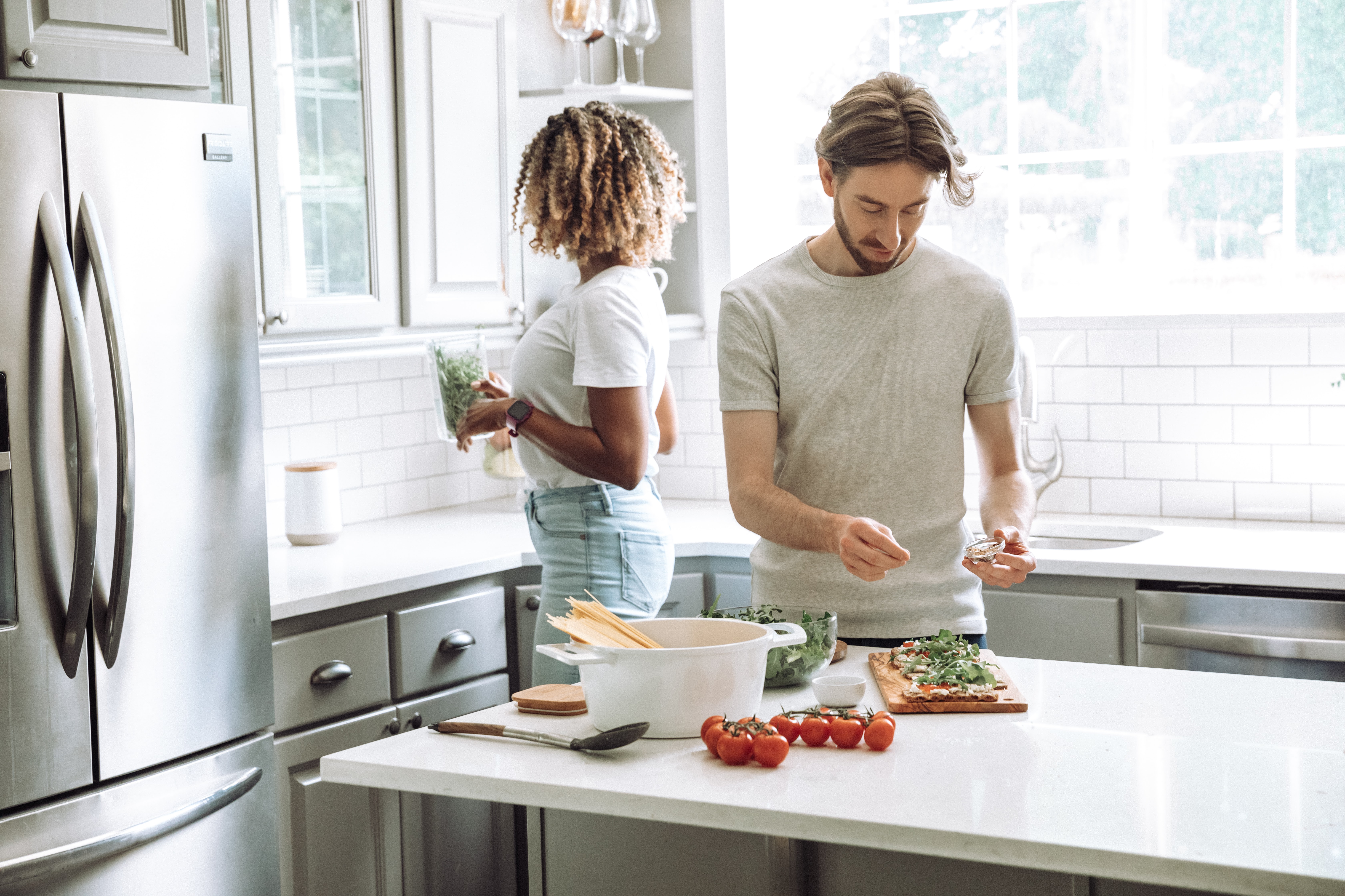 couple cooking in kitchen with large French door refrigerator