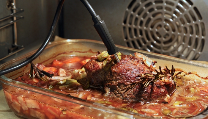 Built-in meat thermometer probe in oven inside dish that is cooking