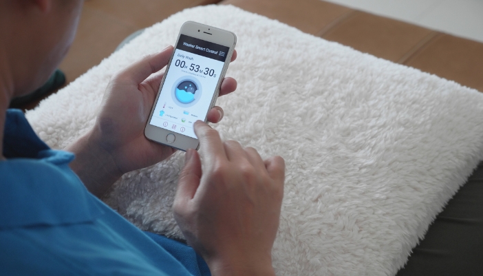 Closeup of a man checking on the status of his laundry with his smart phone