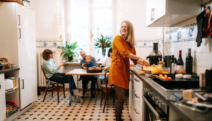 A woman in a gold dress prepares to cook a holiday meal.