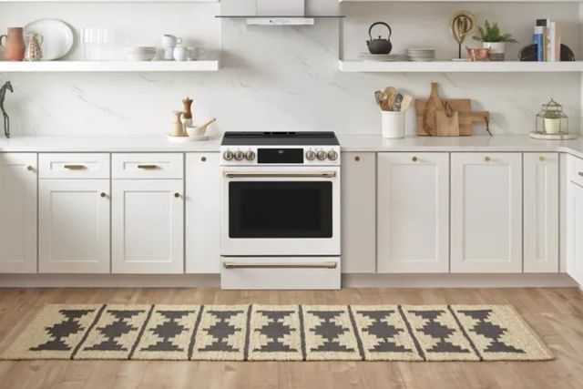 front view of a white and marble kitchen with a cafe induction range in the center