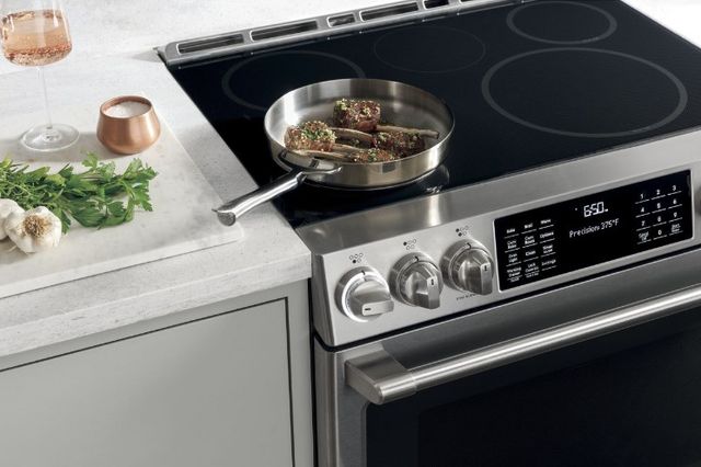 front view of a cafe induction range cooking porkchops with a glass of rose next to it