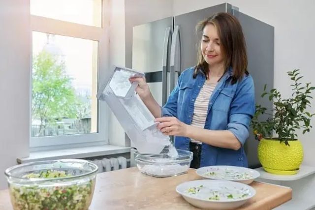 woman standing over her countertop emptying ice from her refrigerator's ice maker to clean it