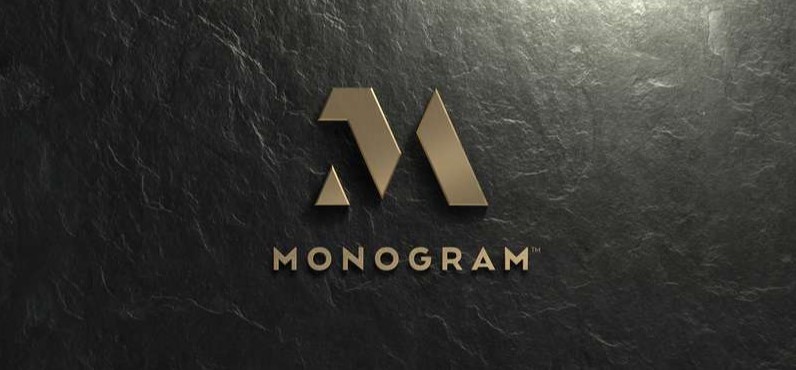 gold Monogram logo on a black stone background