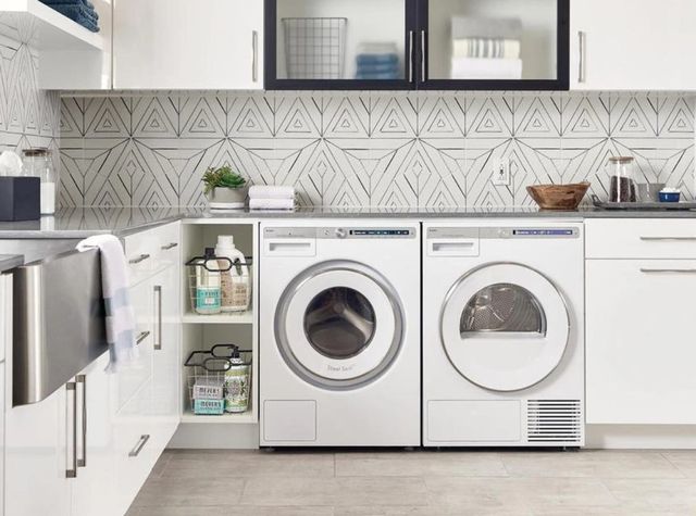 front view of a white washer and steam dryer surrounded by storage in a white laundry room